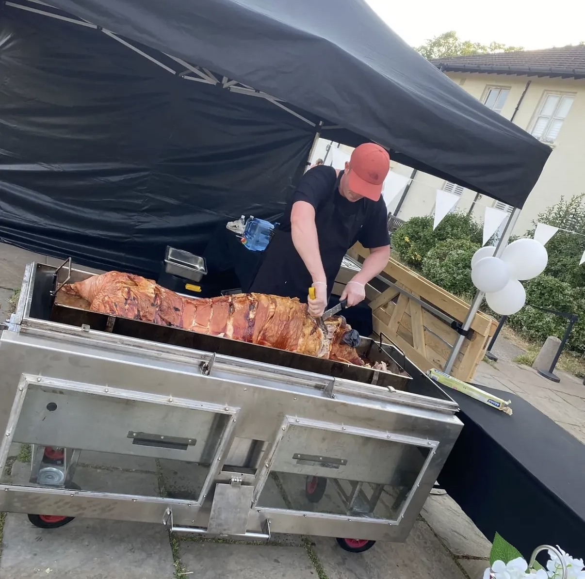 Chef carving whole hog under brass pendant lights